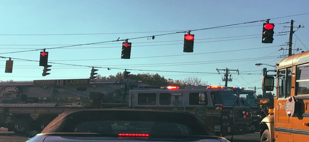 intersection with red lights and fire truck and school bus driving through 